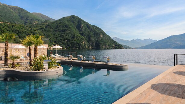 A pool area with lounge chairs and a view of a lake and mountains. - Grand Hotel Victoria Concept & Spa, by R Collection Hotels (Menaggio)