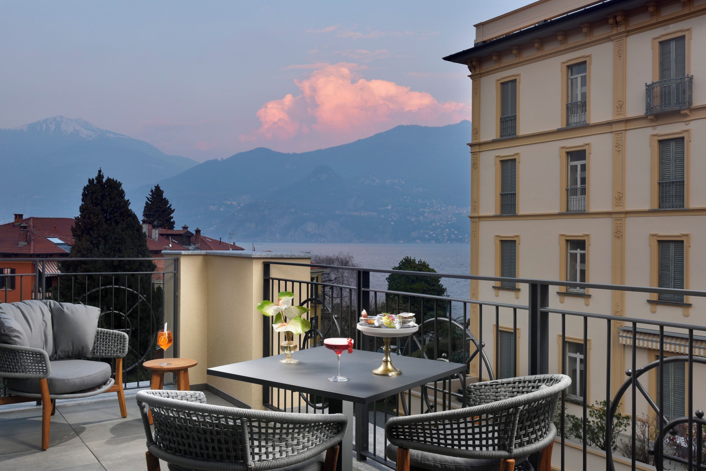 Eine Terrasse mit Korbstühlen, einem Tisch und Blick auf die Berge.