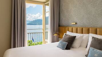 A hotel room with a large bed, a view of the sea, and a patterned wall.