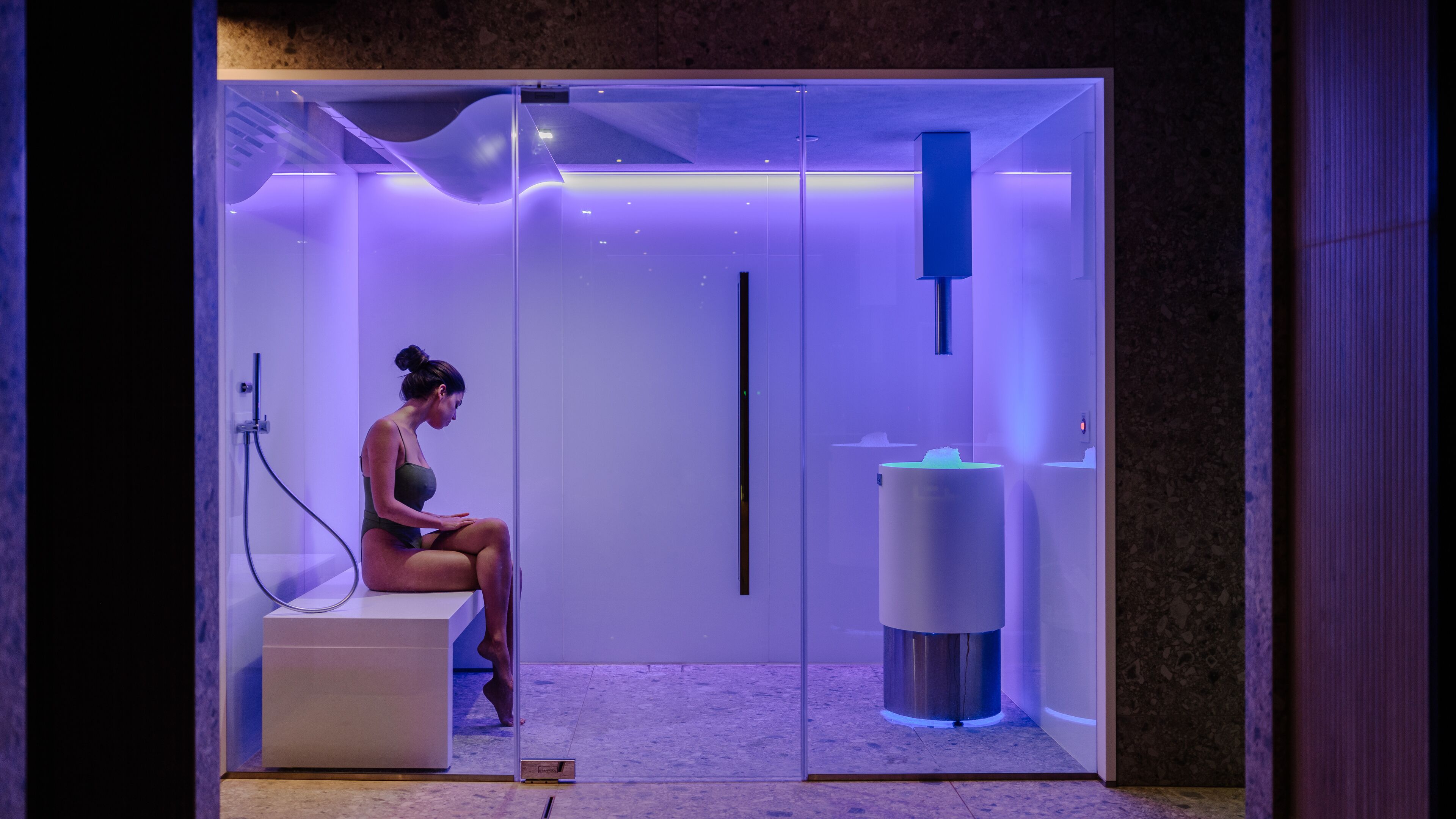 Ein modernes, minimalistisches Badezimmer mit Glasabtrennung, integriertem Waschtisch und Duschbereich.