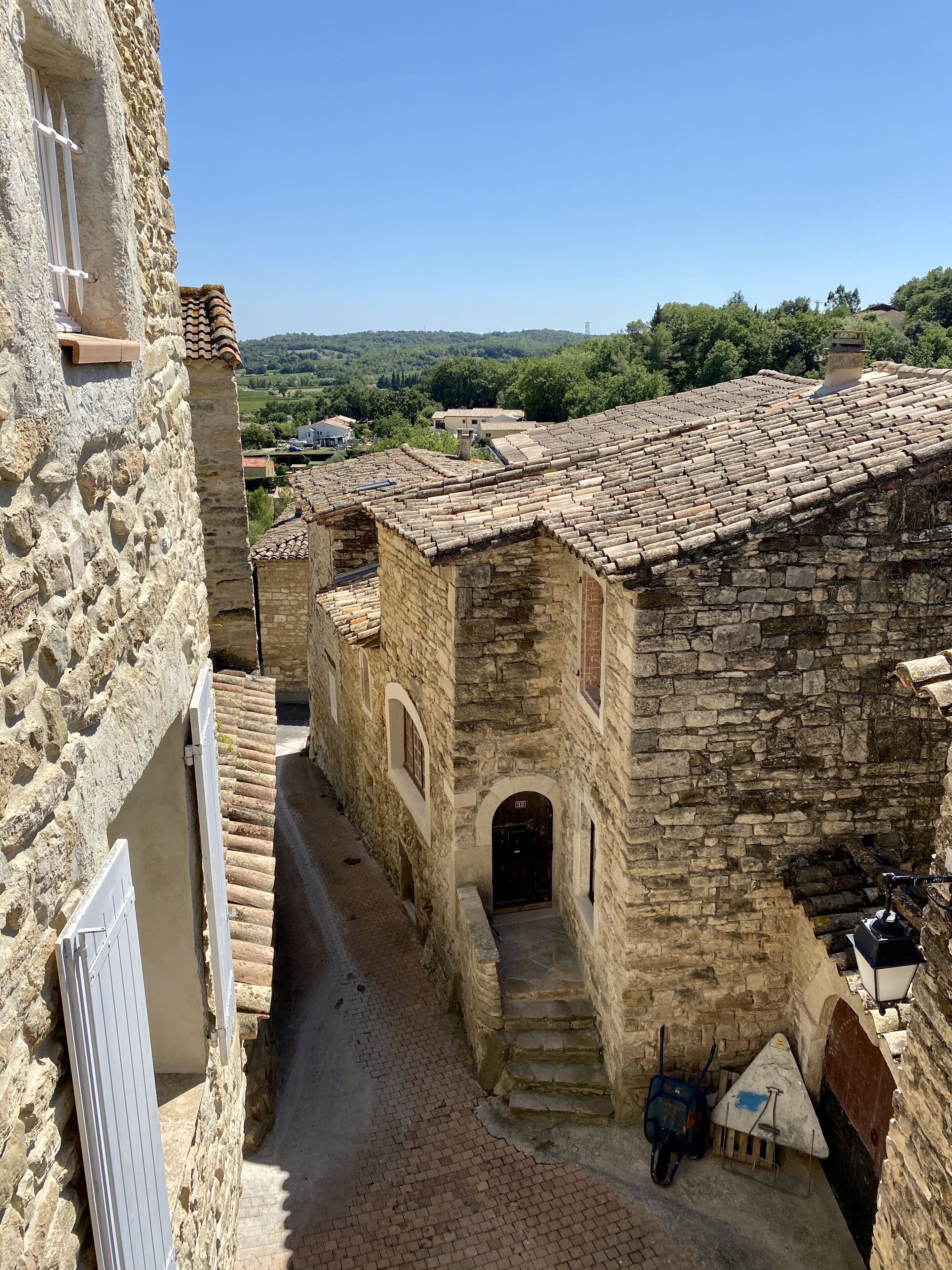 A narrow stone alleyway with traditional stone buildings, a small gate, and a paved path leading to a building entrance.
