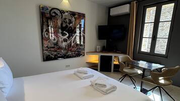 Une chambre d’hôtel avec un grand lit, un bureau avec une chaise, un téléviseur à écran plat et une fenêtre avec des rideaux.