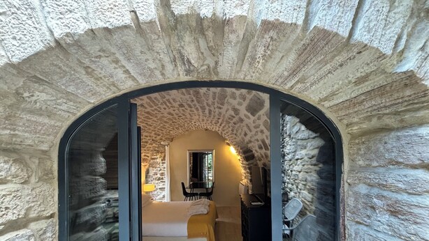 Une pièce aux murs de pierre, avec un lit, un bureau et une chaise.