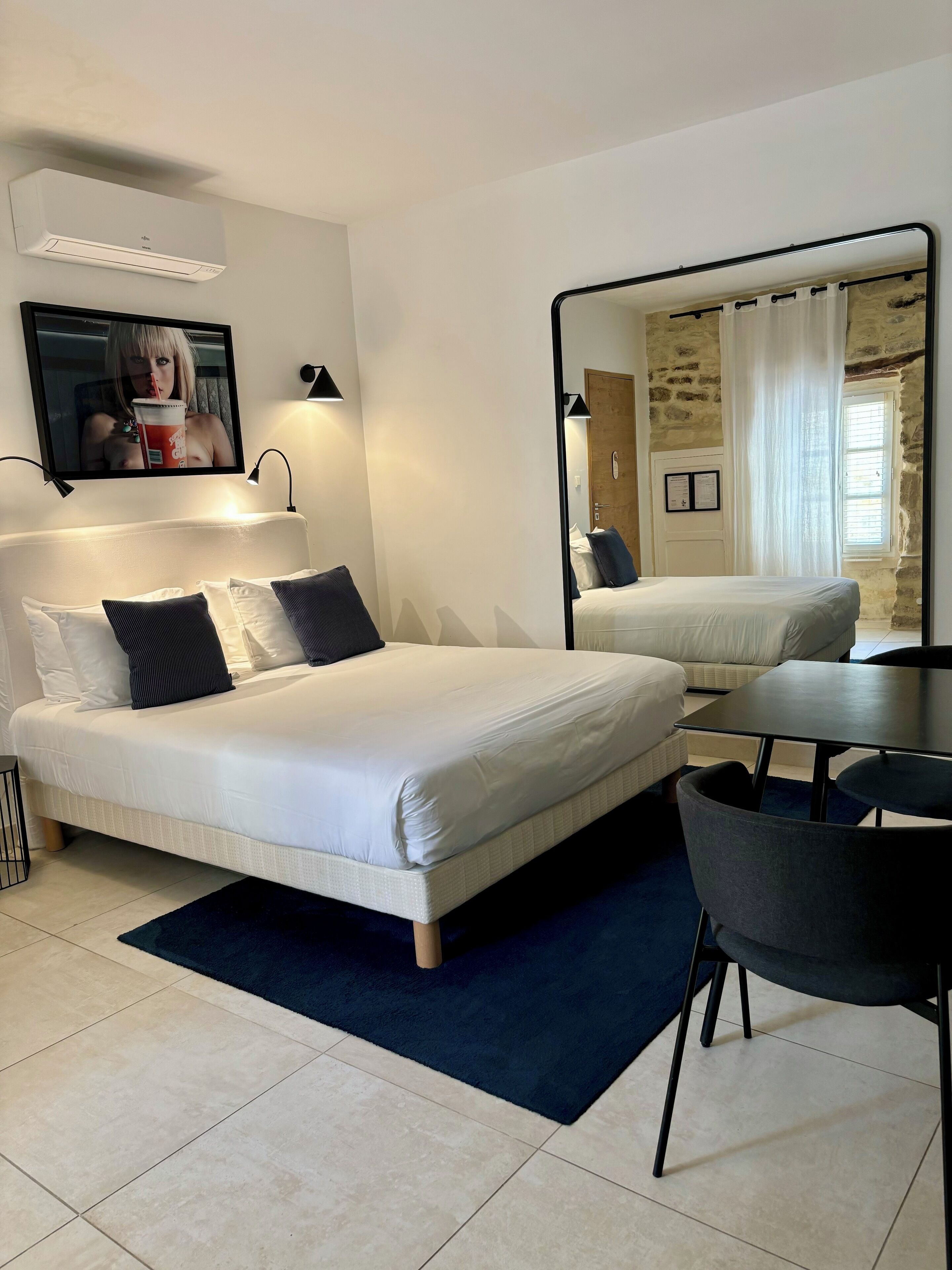 Ein modernes Hotelzimmer mit einem großen Bett, einem Schreibtisch und einem Spiegel.