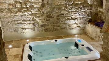 Een badkamer met stenen muren en een rechthoekig hottub.