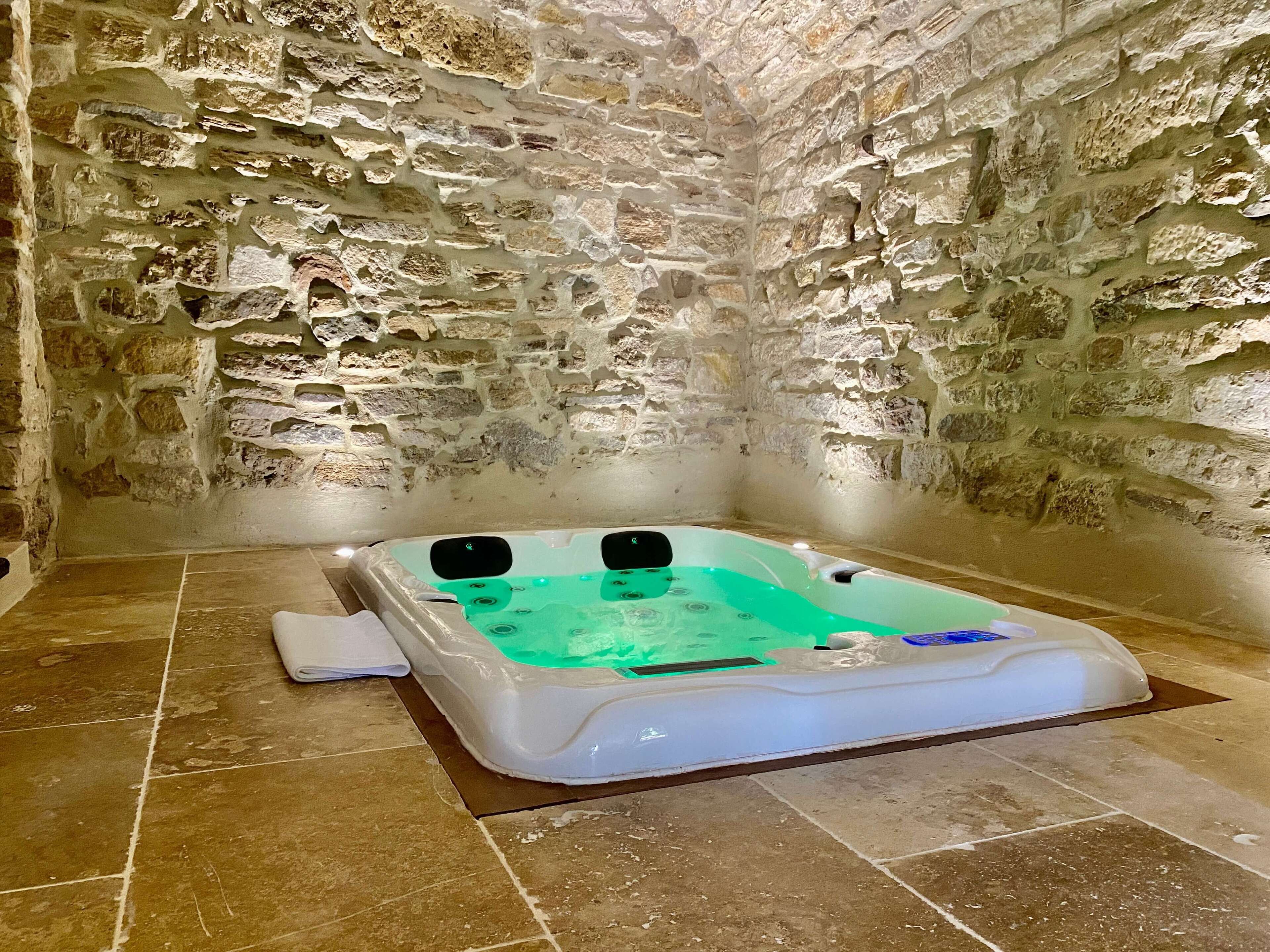 A stone-walled room with a spa tub.