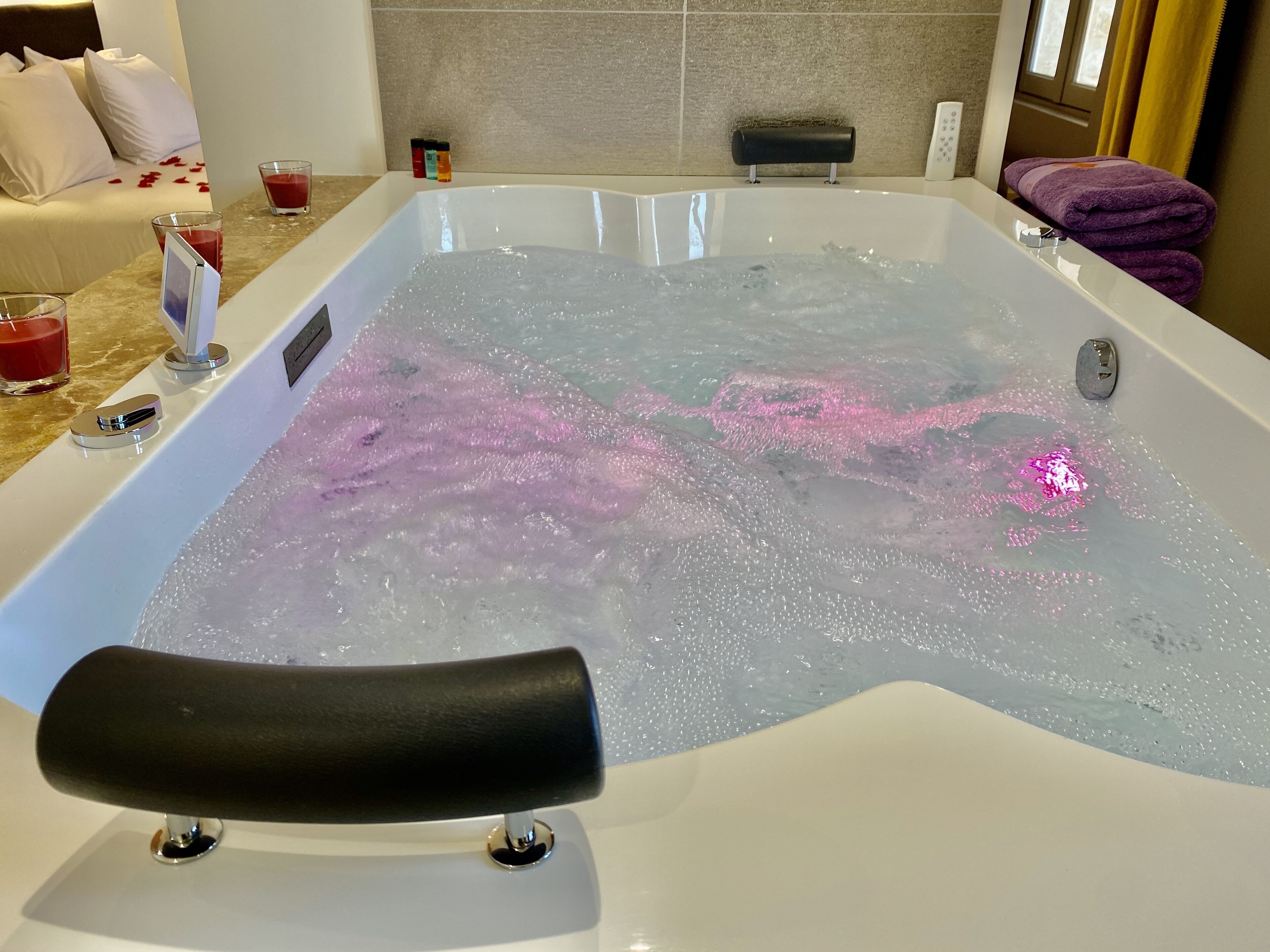 Et badekar med et sort sæde, et kontrolpanel og et rosa lys.