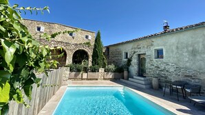 Un bâtiment en pierre doté d’une piscine et d’un espace extérieur aménagé pour s’asseoir.