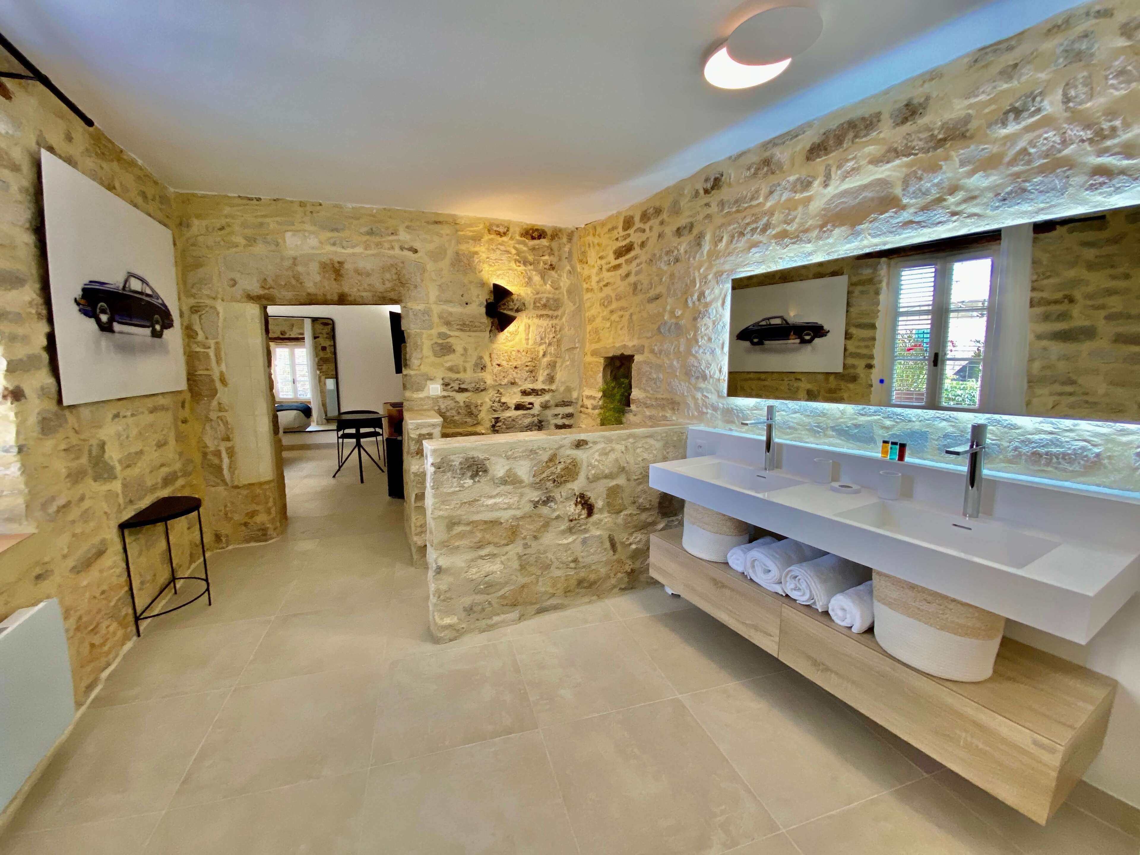 A bathroom with stone walls, a large mirror, and a vanity with multiple sinks.