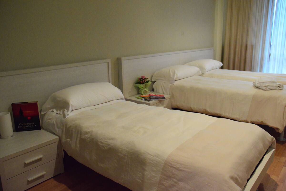 Una habitación de hotel con dos camas, una mesita de noche y una lámpara.