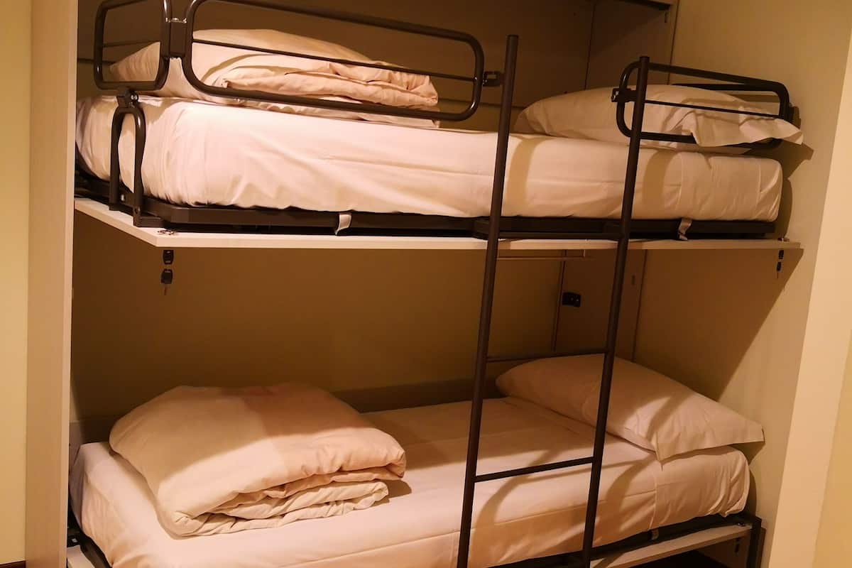 Dormitorio con literas de dos niveles, suelo de madera y un diseño sencillo y funcional.