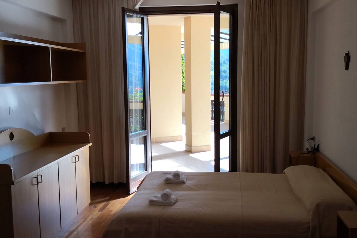 Una habitación de hotel con cama, escritorio y balcón.