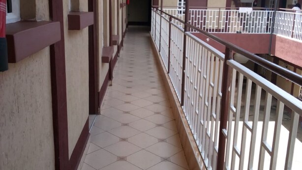 A corridor with tiled flooring and a railing on one side.
