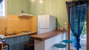 A compact kitchen with a gas stove, white refrigerator, and a small bar area with stools. - Homerez - Charming Apt in Le Luc (Le Luc)