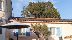 A poolside area with a tiled deck, lounge chairs, a wicker table, and a large umbrella. - Homerez - Charming Apt in Le Luc (Le Luc)