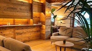 A cozy living area with a sofa, a round coffee table, and a plant. - Parc Hotel Posta (Marebbe)