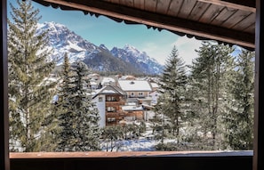 Un refugio de montaña con varios pisos, rodeado de árboles nevados y montañas.