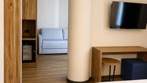 A hotel room with a bed, a desk, a television, a sofa, and a wooden wardrobe. - Parc Hotel Posta (Marebbe)