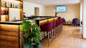 A bar area with a wooden counter, a potted plant, and red bar stools. - Parc Hotel Posta (Marebbe)