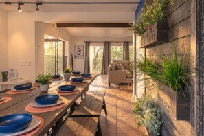 Un espace repas avec une longue table en bois, des bols bleus et des plantes en pot.