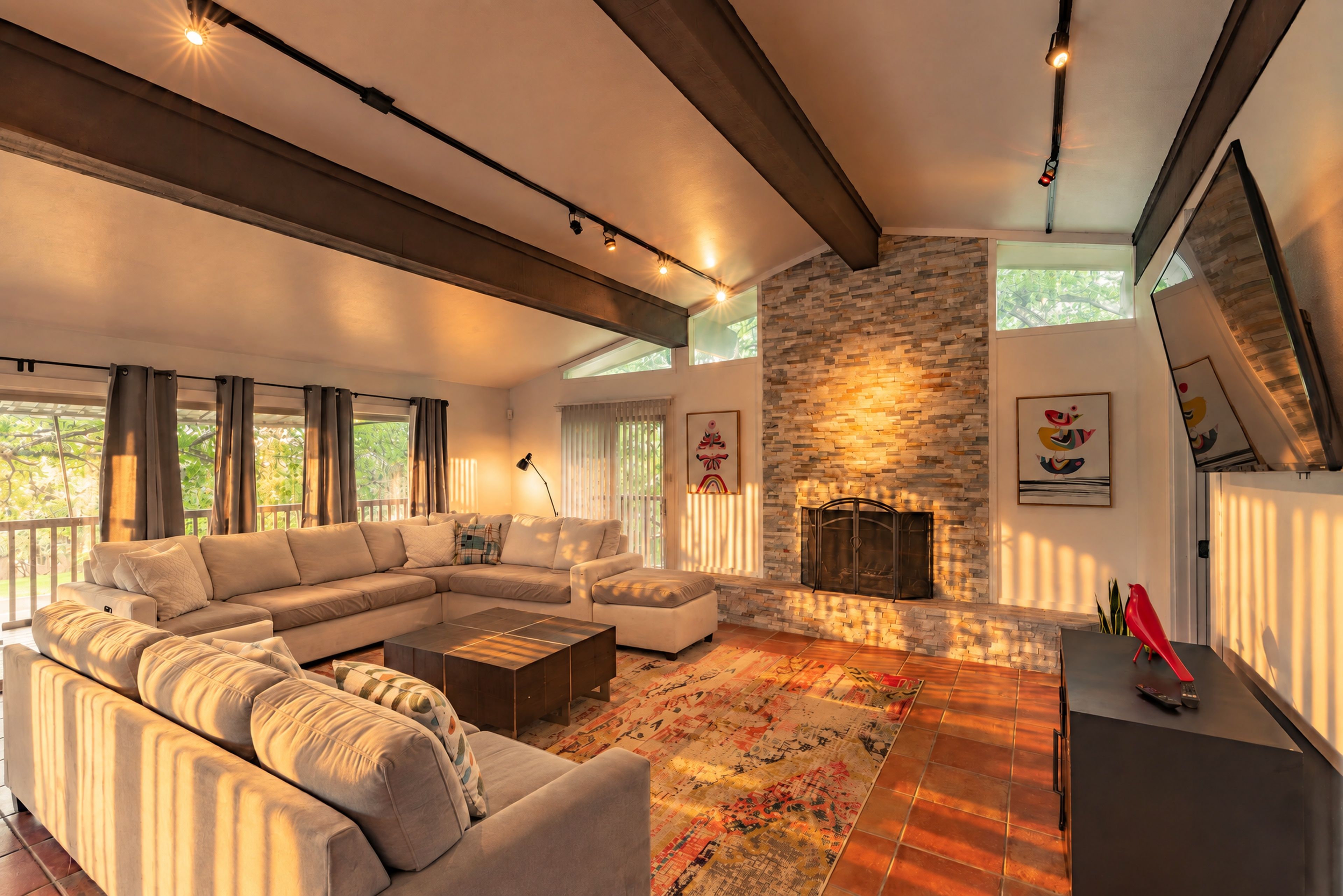 A spacious living room with a large sectional sofa, a fireplace, and a view of the outdoors.