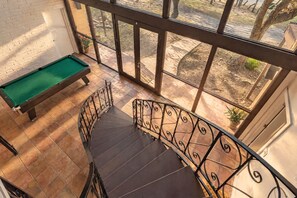 Une table de billard dans une pièce donnant sur un jardin grâce à de grandes fenêtres.