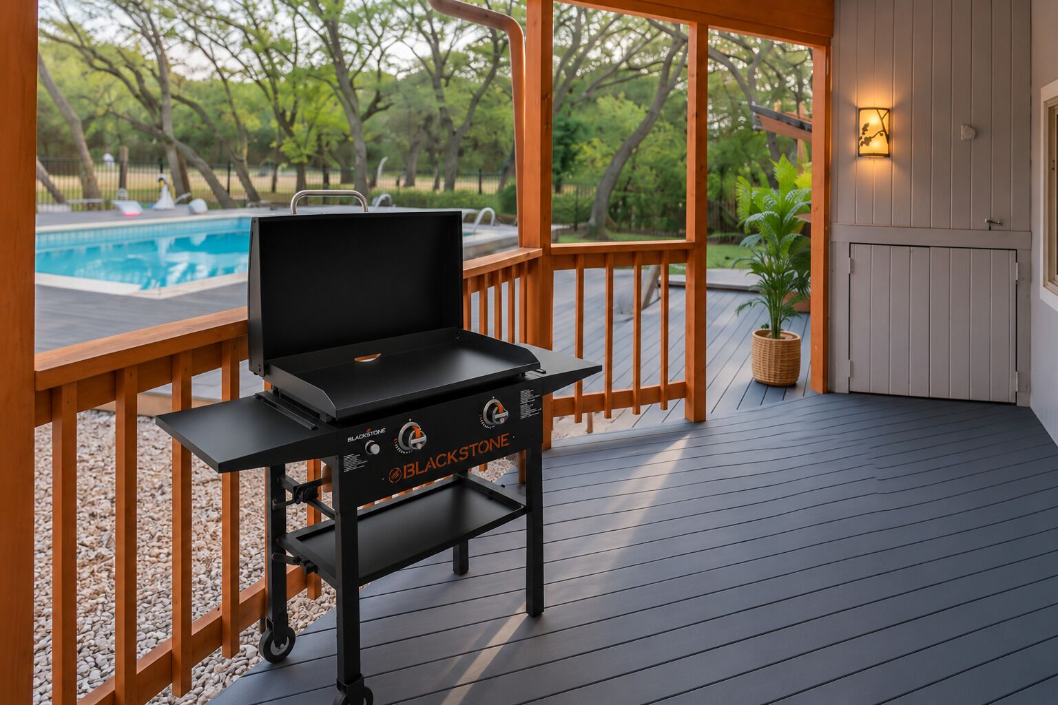 A Blackstone grill on a wooden deck with a pool in the background.