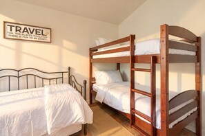 A bunk bed room with a wooden headboard, a single bed, and a wall-mounted sign.