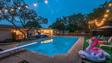 Ein Garten mit Schwimmbad, Liegestühlen und Lichterketten.