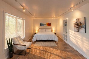 A bedroom with a bed, bedside lamps, a chair, a potted plant, and artwork on the walls. - 6BR Retreat with Huge Private Pool, Game Room & 1-Acre Backyard (San Antonio)