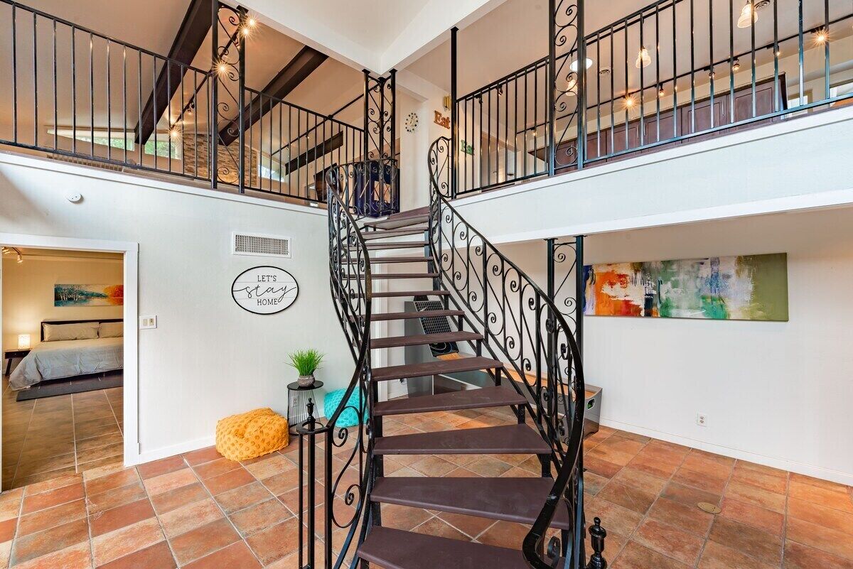 Ein geräumiges Interieur mit einer zentralen Treppe, einem Essbereich und einem Wohnzimmer mit einem Bett.