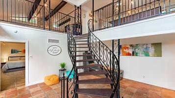 Ein geräumiges Interieur mit einer zentralen Treppe, einem Essbereich und einem Wohnzimmer mit einem Bett.
