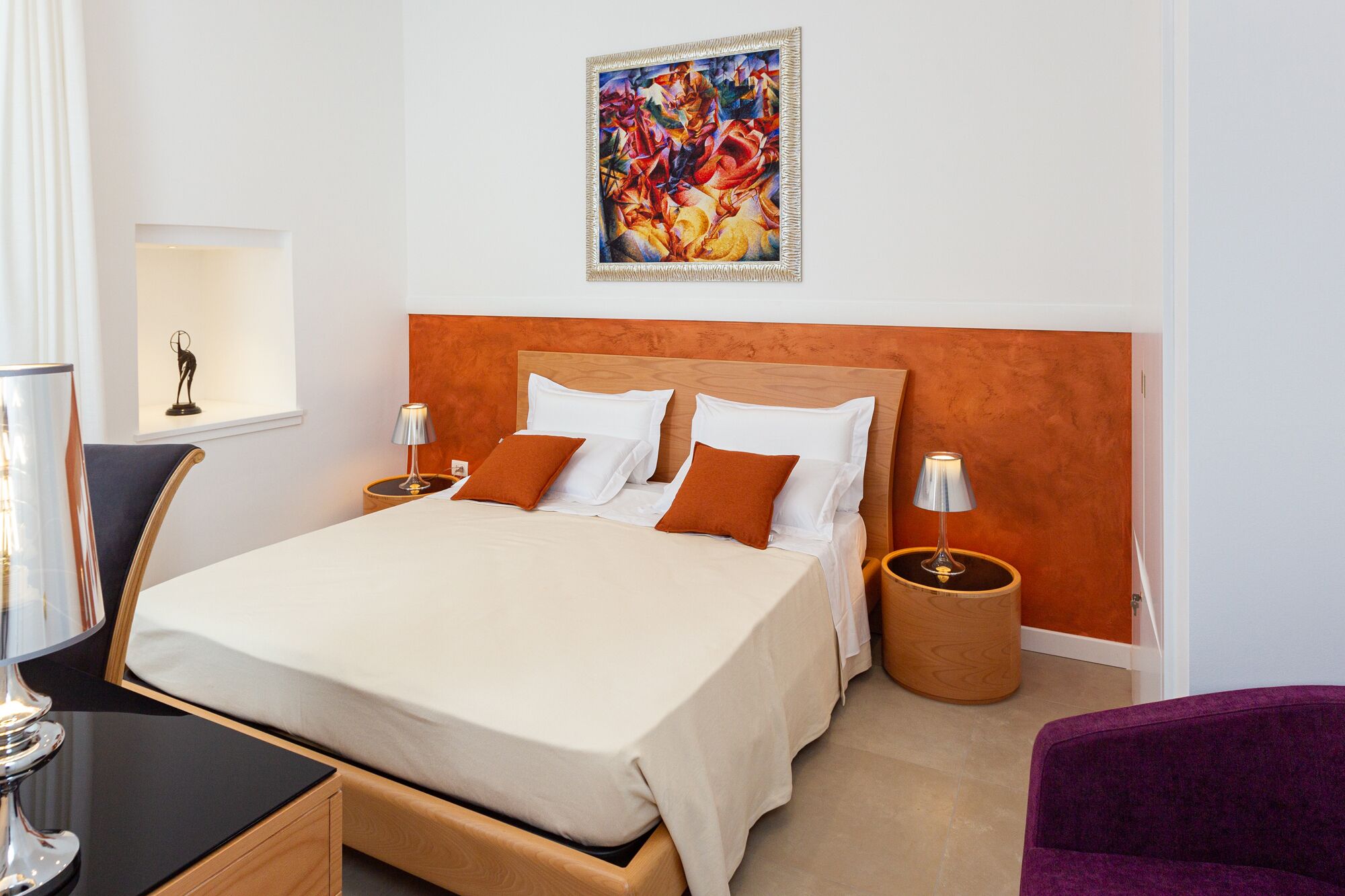 A hotel room with a large bed, two bedside tables, a chair, and a painting on the wall.