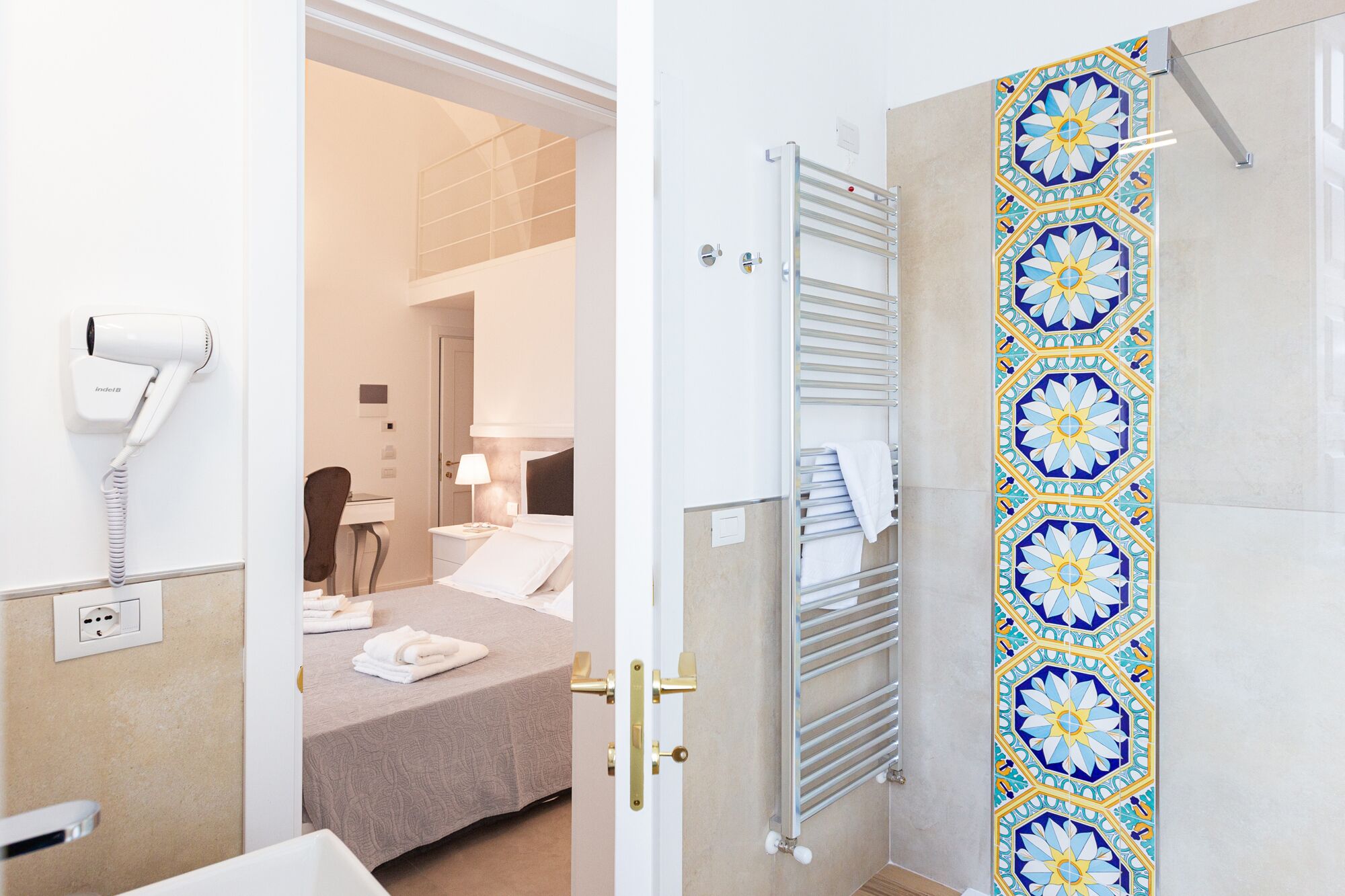 Een hotelkamer met een bed, een handdoekhouder, een haardroger en een decoratieve wand van tegels.