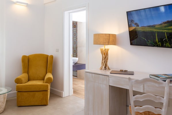 Una sala de estar moderna con un sillón amarillo, un escritorio blanco, una lámpara y un cuadro de un paisaje.
