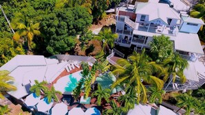 A resort with multiple swimming pools, palm trees, and a large building with balconies. - "O Coeur de Deshaies" (Deshaies)