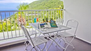 A balcony with a white metal table and chairs, a book, and two drinks. - "O Coeur de Deshaies" (Deshaies)