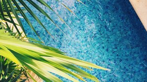 Ein Swimmingpool mit klarem, blauem Wasser und Palmen im Vordergrund.