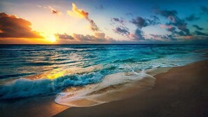Ein Strand mit Wellen und einem Sonnenuntergang.
