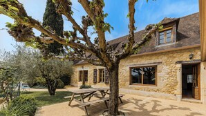 A stone building with a large tree in front, a picnic table, and a small garden. - Villa Paola, beautiful holiday home with a large fenced private swimming pool. (Saint Rabier)