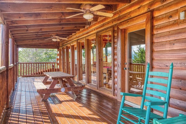 A wooden deck with a picnic table and chairs, a ceiling fan, and large windows. - Luxury! 2 Master Suites w/Fireplaces|Game Room (SEVIERVILLE)
