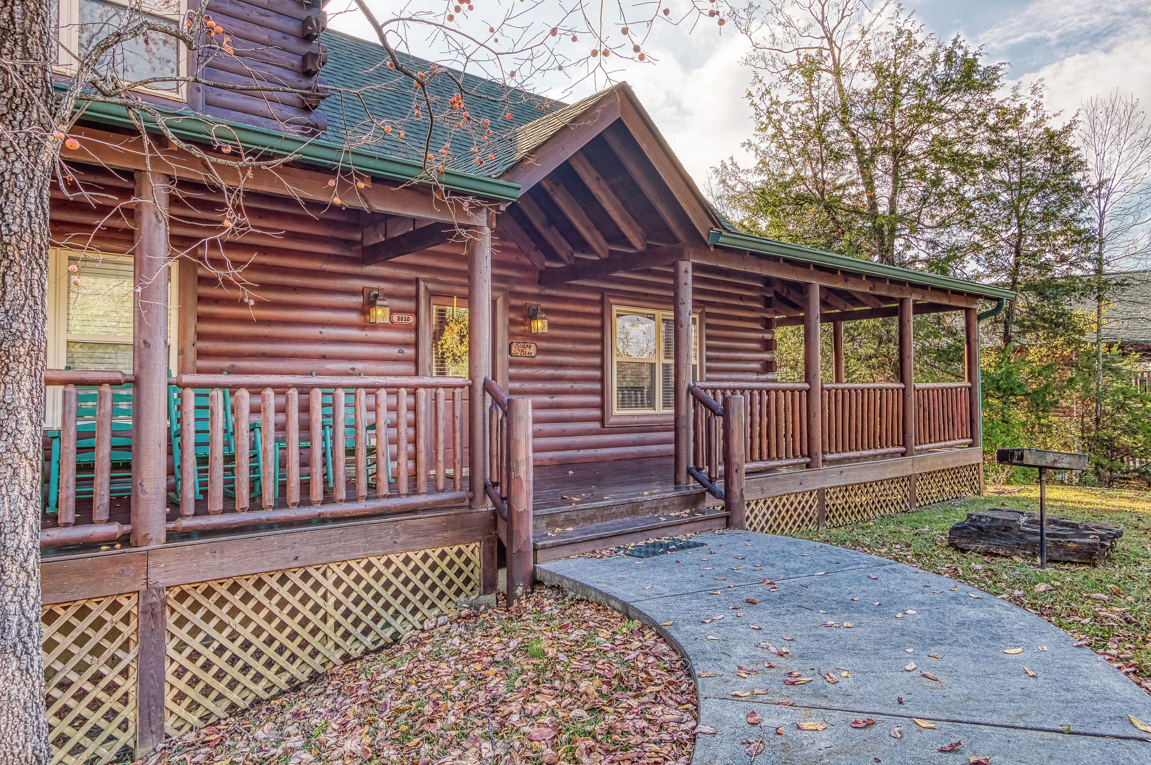 A rustic log cabin with a porch, a covered entryway, and a small outdoor seating area.