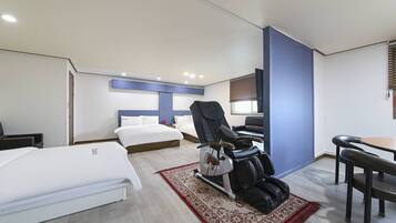 Una habitación de hotel con cama, sillón de masajes, escritorio y una silla.