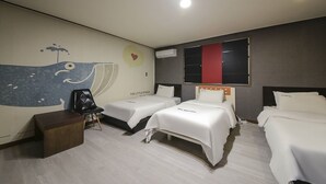 Habitación de hotel con dos camas, una mesita de noche de madera, un mural en la pared y una ventana con un panel rojo.