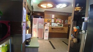 Un vestíbulo de hotel con una recepción, un refrigerador, un microondas y una pequeña mesa con una máquina de café.