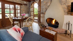A cozy living room with a stone fireplace, wooden furniture, and a view through a large window. - Cal Carulla (Pujalt)