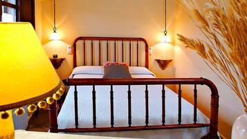 Una cama con cabecera de madera, dos lámparas de noche y una lámpara decorativa a la izquierda.
