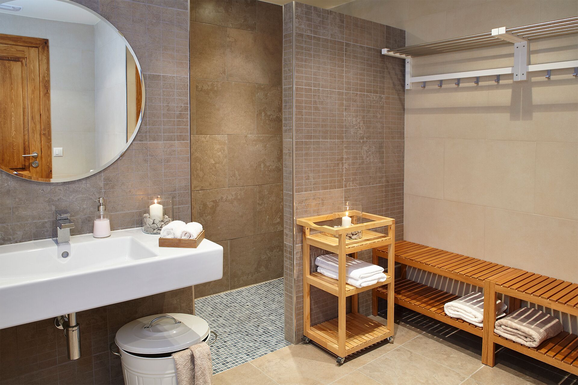 Une salle de bain moderne avec un lavabo blanc, un meuble-lavabo en bois, un miroir et un banc avec des serviettes.