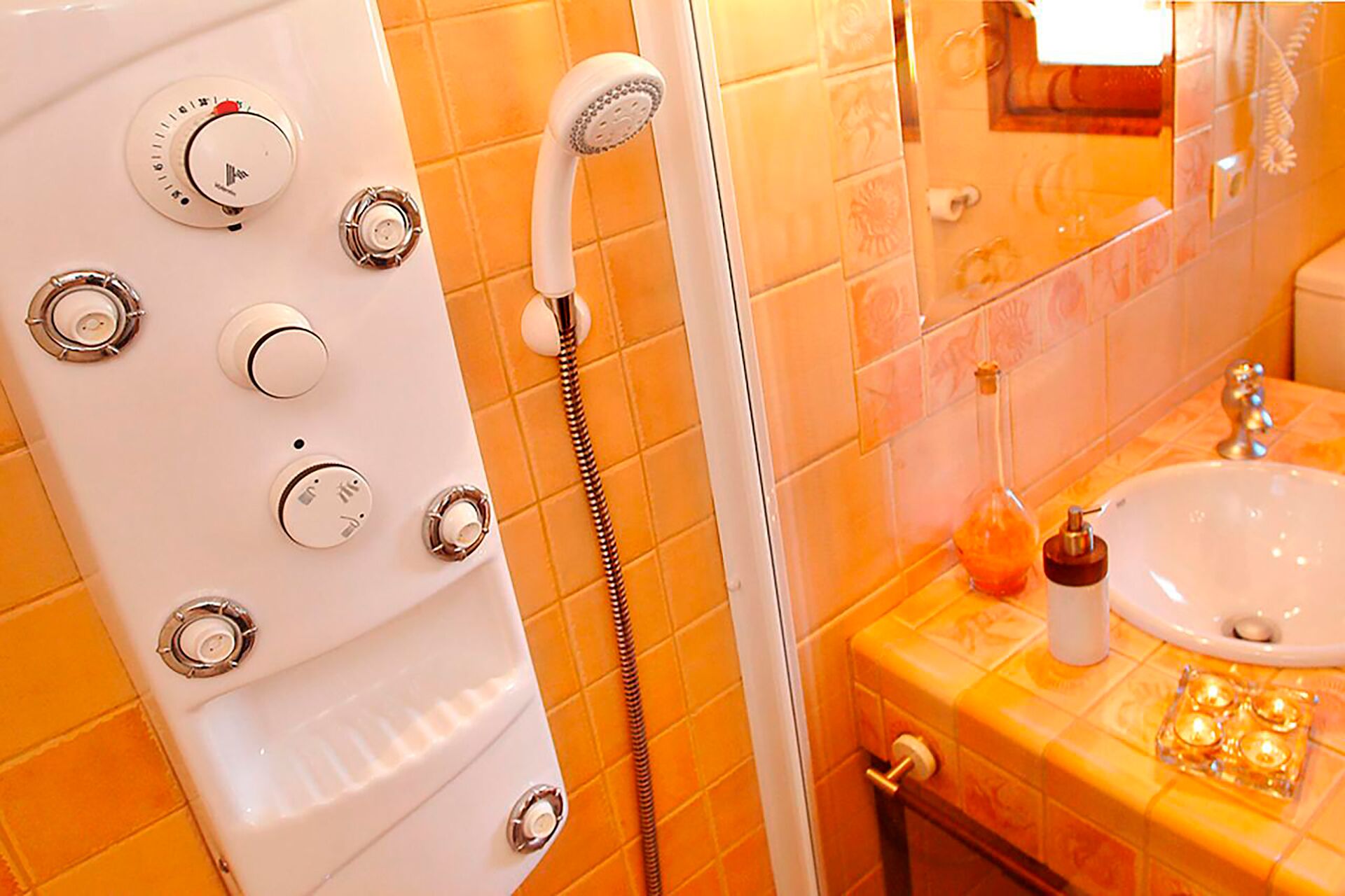 Un bagno con una vasca da bagno bianca, una doccia con soffione a mano e un lavandino con dispenser di sapone.