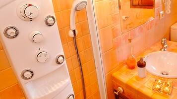 Un bagno con una vasca da bagno bianca, una doccia con soffione a mano e un lavandino con dispenser di sapone.
